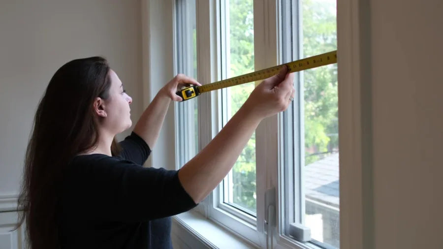 A woman measuring the inside width of a window recess